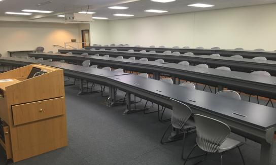 Large stadium style classroom with tables and chairs.