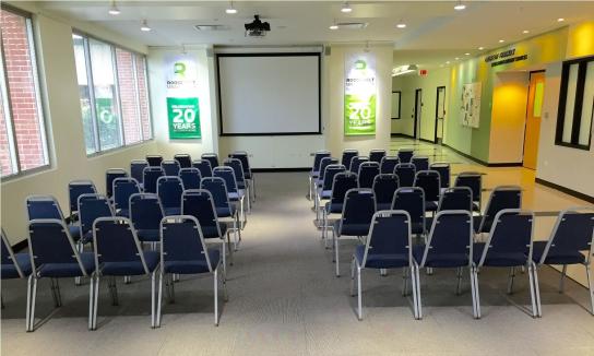 Open area featuring rows of chairs directed towards a projector screen.